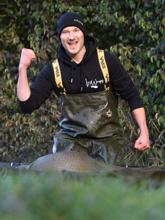 Erfolgreicher Karpfenangler mit Hoodie und Cap von 27Wraps.